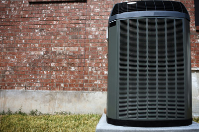 Air conditioning unit outside of brick home. Multnomah Heating will repair your air conditioner condenser if you live in the Portland, OR and Gresham, OR area.