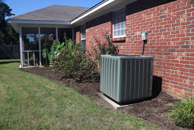 Air conditioner unit outside of brick home. Multnomah Heating will repair your air conditioner capacitor in the Portland, OR area.